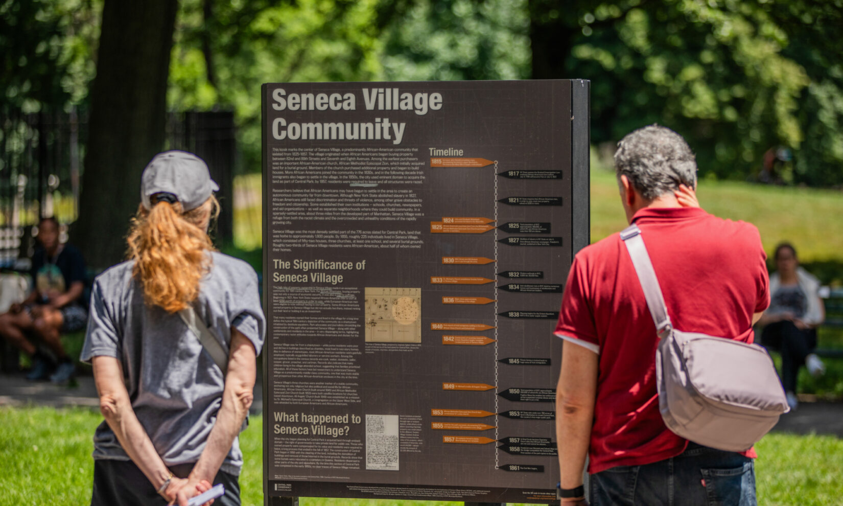 Visitors reading about the Seneca Village Community information.