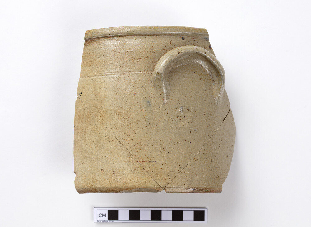 A photo of a shard of a tan stoneware jar with a handle.