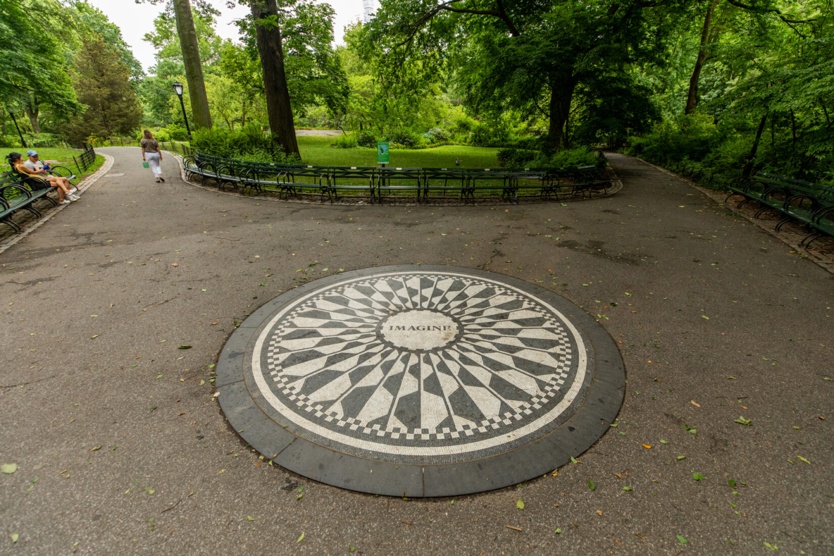 A pathway with a circular, black-and-white mosaic that says “Imagine” in the center.